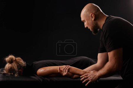 Photo for Male masseur giving a hand massage to a girl on a dark background, hand massage - Royalty Free Image