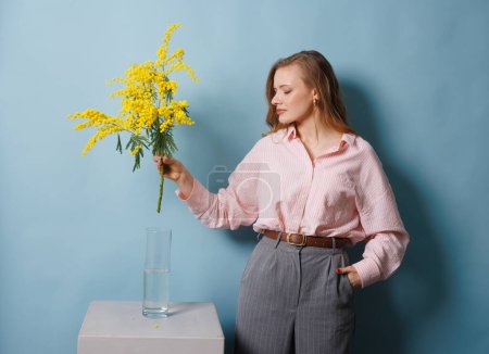 girl holds a mimosa branch in her hand and puts it in the water, spring concept