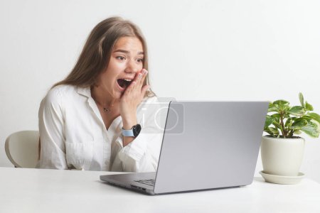 chica feliz con una computadora portátil se regocija en un trabajo exitoso trabajando en la oficina, negocio exitoso, ganar en línea, decisión exitosa