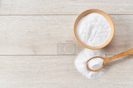Foto de Tazón con bicarbonato de sodio en una mesa de madera blanca, vista superior. - Imagen libre de derechos
