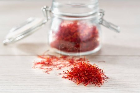 Photo for Saffron thread in a glass storage jar, on a wooden table. - Royalty Free Image