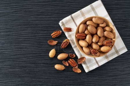 Photo for Wooden plate with pecan nuts on black table. Space for text - Royalty Free Image