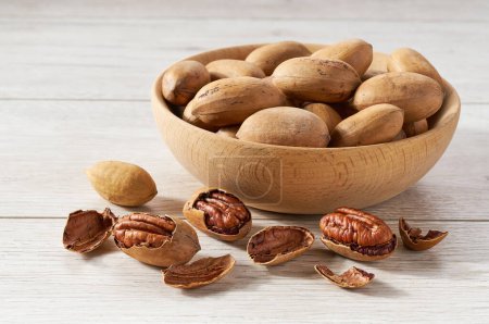 Photo for Wooden plate with pecan nuts on white table. - Royalty Free Image
