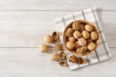 Photo for Wooden plate with walnuts nuts on white table. Space for text - Royalty Free Image