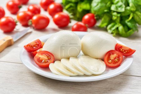 Foto de Bolitas de queso mozzarella italiano suave blanco, tomates rojos maduros de cereza y hierba de albahaca verde fresca, listo para hacer ensalada caprese - Imagen libre de derechos