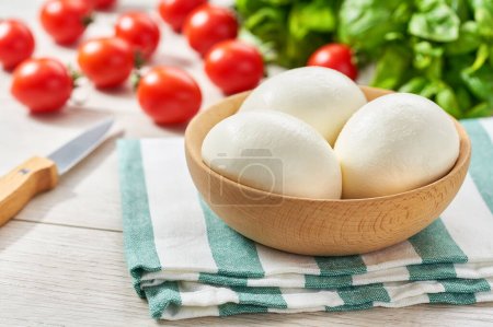 Photo for White ball of Italian soft cheese mozzarella di Bufala Campana served with fresh green basil and red tomato,  ingredients for caprese salad. - Royalty Free Image