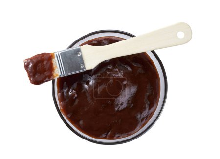 Foto de Barbecue sauce in a saucer with basting brush isolated on a white background. Glass dish of barbecue sauce with basting brush - Imagen libre de derechos