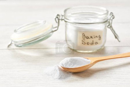 Photo for Baking soda in a wooden spoon on a white wooden table. - Royalty Free Image