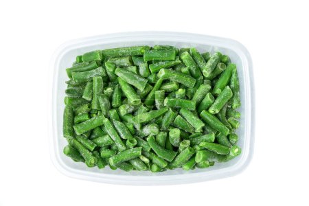 Foto de Frijoles verdes congelados en un recipiente de plástico, almacenando verduras para el almacenamiento de invierno. Alimentos congelados vegetales. Frijoles verdes congelados en un recipiente de plástico. Congelación profunda de verduras. - Imagen libre de derechos