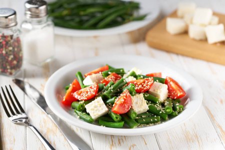 Téléchargez les photos : Cuisson de salade de haricots verts avec tomates, feta et graines de sésame. - en image libre de droit