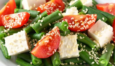 Foto de Ensalada de judías verdes con feta en un plato blanco. Ensalada de judías verdes y tomate en plato blanco. - Imagen libre de derechos
