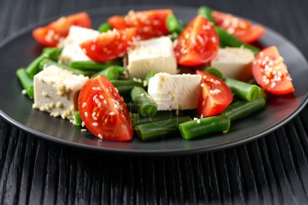 Téléchargez les photos : Salade de haricots verts et tomates sur assiette noire. - en image libre de droit