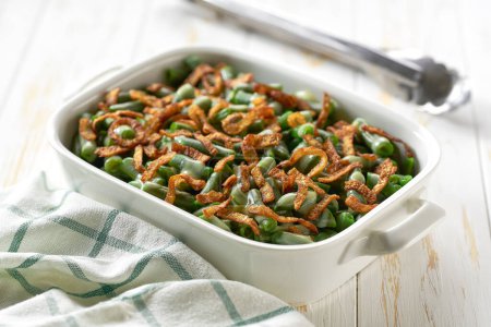 Photo for Green bean casserole sprinkled with crispy fried onions served on ceramic cooking baking dish. - Royalty Free Image