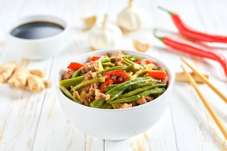 Photo for Fragrant spicy Chinese food minced ground pork belly stir fried with pickled yard long beans and red chili peppers on a wooden table. - Royalty Free Image