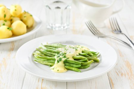 Téléchargez les photos : Haricot vert avec sauce crème et pommes de terre bouillies sur table blanche, mise au point sélective - en image libre de droit