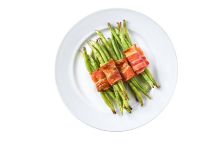 Téléchargez les photos : Faisceau cuit de haricots verts enveloppé dans un bacon sur un bol blanc isolé. Haricots verts roulés dans du bacon et cuits au four. - en image libre de droit