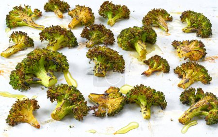 Téléchargez les photos : Brocoli vert rôti maison à l'huile d'olive et aux épices sur une plaque à pâtisserie foncée. - en image libre de droit