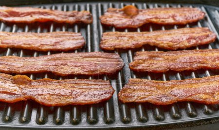 Photo for Cooking bacon on the grill, top view. Smoked bacon is grilled. - Royalty Free Image