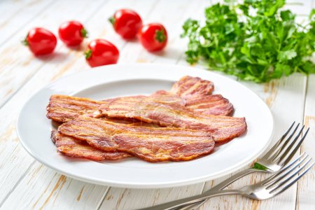 Photo for Plate with fried bacon and bbq sauce on a table, copy space for text. Plate with fried bacon on white kitchen table. - Royalty Free Image