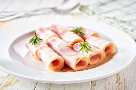 Foto de Rollos de carne de cerdo ahumada en un plato sobre una mesa blanca - Imagen libre de derechos