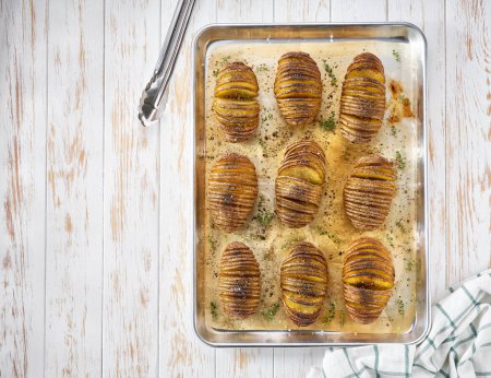 Photo for Traditional baked Hasselback potato on a baking tray on wooden table , top view. Copy space for text. - Royalty Free Image