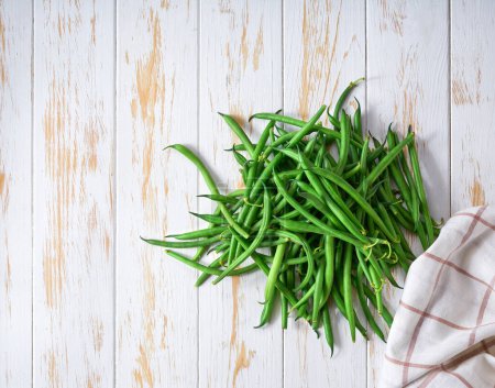 Photo for Organic green beans on a white wooden table, top view. - Royalty Free Image
