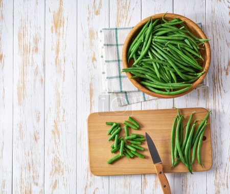 Photo for Whole and chopped fresh green beans on a on a white cuisine table, top view. - Royalty Free Image