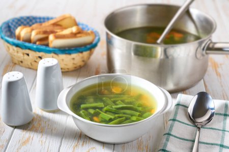 Téléchargez les photos : Délicieuse soupe de haricots verts sur une table en bois blanc. - en image libre de droit