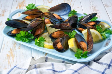 Photo for Close up of a plate with freshly cooked mussels on white table, selective focus. - Royalty Free Image