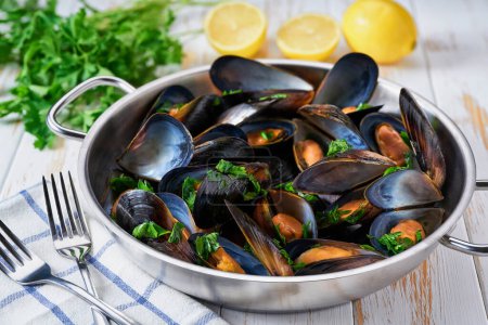 Photo for A frying pan of gourmet mussels is served on a napkin garnished with lemon slices. - Royalty Free Image