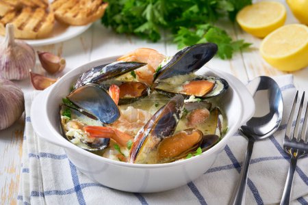 Téléchargez les photos : Délicieuse soupe méditerranéenne de fruits de mer aux moules et crevettes sur une table blanche. - en image libre de droit