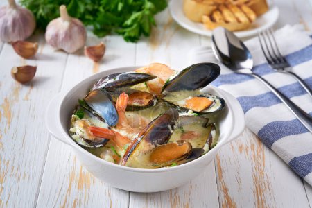 Téléchargez les photos : Soupe crémeuse aux moules de fruits de mer et crevettes sur une table blanche. - en image libre de droit