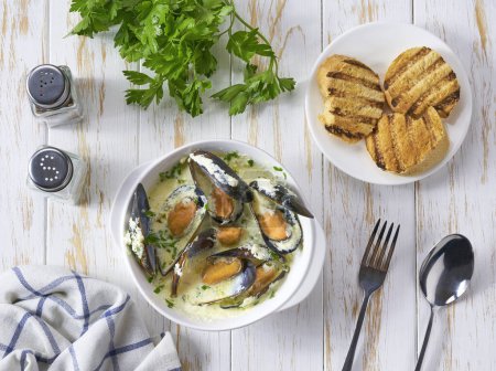 Téléchargez les photos : Chowder - délicieuse soupe de poisson aux moules dans un bol sur une table en bois blanc. - en image libre de droit