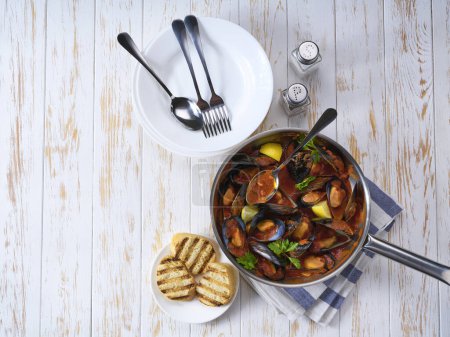 Téléchargez les photos : Moules cuites maison avec sauce tomate, ail, herbes italiennes, vin blanc et basilic frais dans une casserole, vue sur le dessus. - en image libre de droit