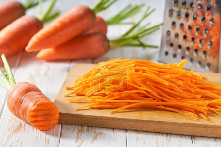 Photo for Grated  organic carrots on a cutting board,  selective focus, rustic style. - Royalty Free Image