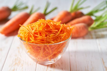Photo for Fresh grated carrots on a white wooden table, selective focus. - Royalty Free Image