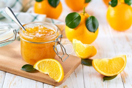 Photo for Homemade orange confiture in a jar on a white wooden table. Delicious homemade natural orange jam. - Royalty Free Image