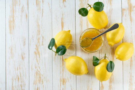 Photo for Homemade lemon confiture in a jar on a white wooden table , top view. Delicious homemade natural lemon jam for toast, top view. - Royalty Free Image