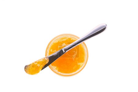 Téléchargez les photos : Vue de dessus de la confiture d'orange dans un bocal avec couteau isolé sur fond blanc. Pot de confiture orange avec vue sur le dessus du couteau, isolé sur fond blanc. - en image libre de droit
