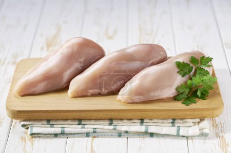 Photo for Raw chicken breasts on a white wooden table. Organic farm poultry. Fresh fillet. Place for text - Royalty Free Image