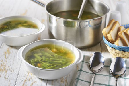 Téléchargez les photos : Soupe de haricots verts maison avec des légumes sur une table en bois, fermer. Le concept d'une alimentation saine et adéquate. - en image libre de droit