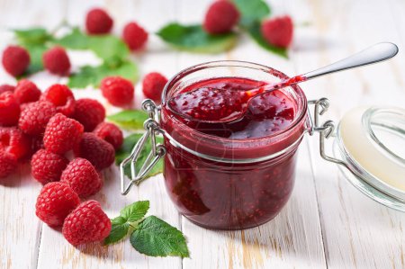 Photo for Sweet raspberry jam in jar with juicy fresh berries on wooden table. Delicious homemade natural raspberry jam. - Royalty Free Image