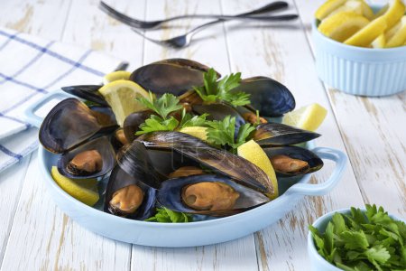 Photo for Close up of a plate with cooked mussels on white table, selective focus. - Royalty Free Image