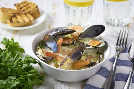Téléchargez les photos : Délicieuse soupe méditerranéenne de fruits de mer aux moules et crevettes sur une table blanche. - en image libre de droit