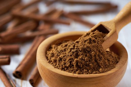 Photo for Cinnamon powder in a wooden bowl  on a white wooden table. - Royalty Free Image