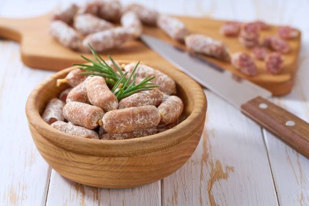 Photo for Mini smoked sausages in wooden bowl on a white wooden table. Mini Chorizo - Royalty Free Image