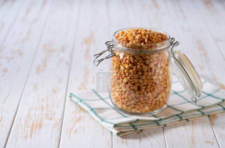 Photo for Dry yellow peas in glass storage jar on a light table. - Royalty Free Image
