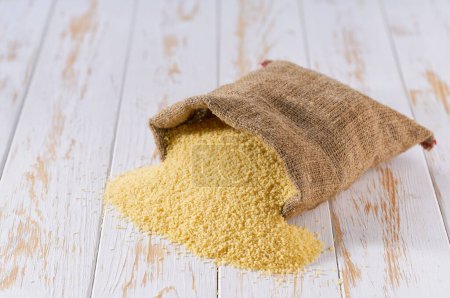 Photo for Organic couscous in sack bag. Sack with organic couscous . Dry couscous in burlap bag and heap of couscous. - Royalty Free Image