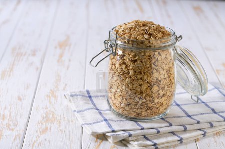 Photo for Organic dry rolled oats  in glass storage jar on a light table. - Royalty Free Image