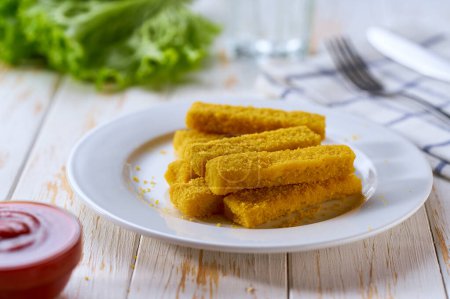 Photo for Fried fish sticks or fish fingers on a wooden table.   Snack food. Crispy golden fried fish fingers sticks with lemon and tomatoe sauce on wooden table. - Royalty Free Image